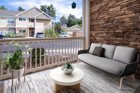 A patio with a couch, table, and potted plants.