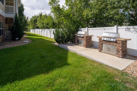 A white fence surrounds a grassy area with two stone pillars in front.