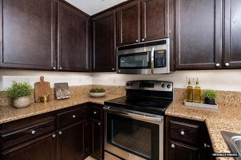A kitchen with dark brown cabinets and a black stove top oven.