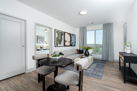 A modern dining room with a round table and grey chairs.