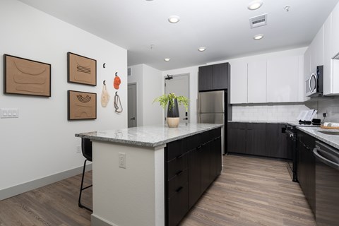 A kitchen with a white counter top and black cabinets.