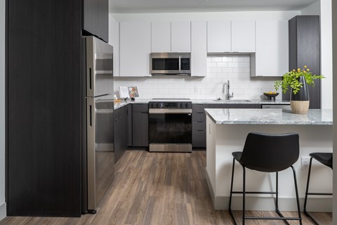 A modern kitchen with a black refrigerator and white cabinets.