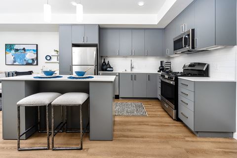 a kitchen with gray cabinets and an island with two stools