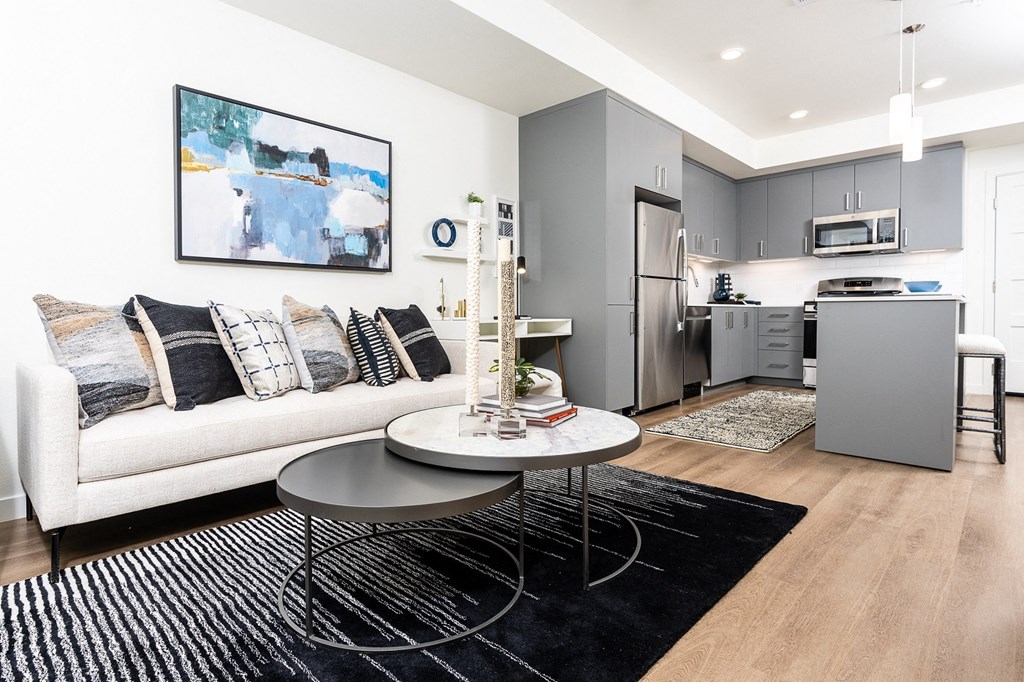a living area with a couch coffee table and a kitchen in the background