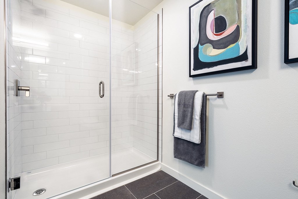 a bathroom with white tiles and a glass shower door