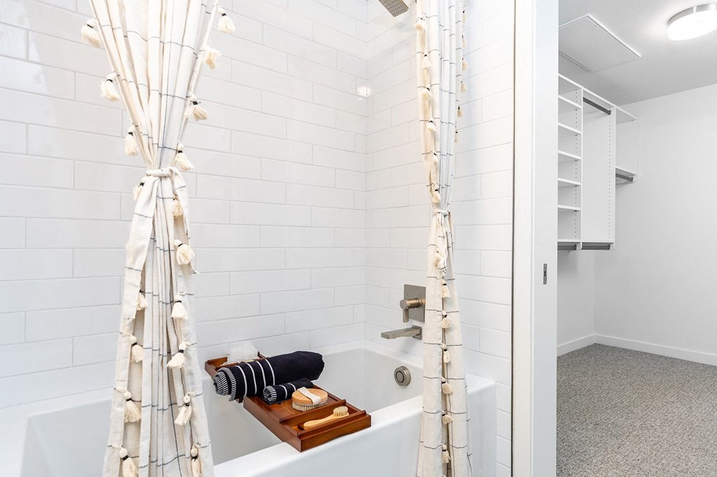 a bathroom with white tiles and a shower curtain with white lights