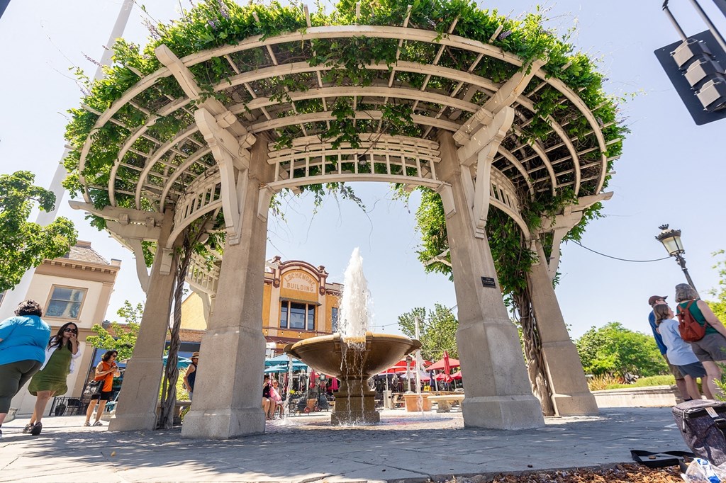 a fountain under a trellis in the middle of a plaza