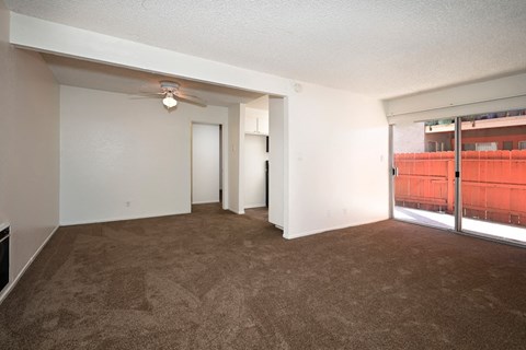 an empty living room with a ceiling fan and a window
