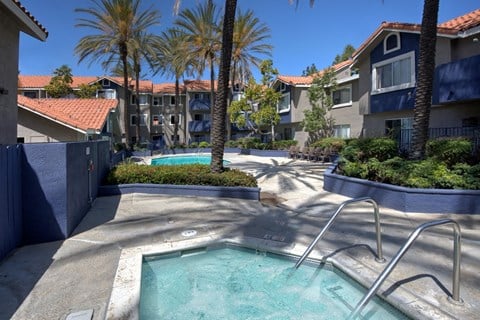 a swimming pool with palm trees in front of an apartment building