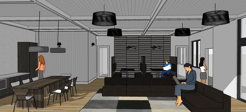 A man is sitting on a couch in a room with a table and chairs.