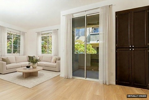 A living room with a white couch, a coffee table, and a glass door leading to a balcony.