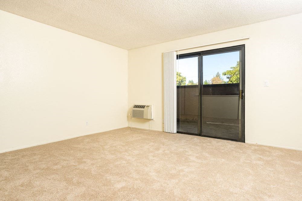 an empty living room with a sliding glass door to a patio