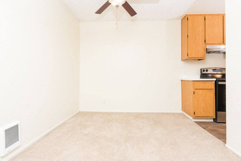 an empty living room with a ceiling fan and