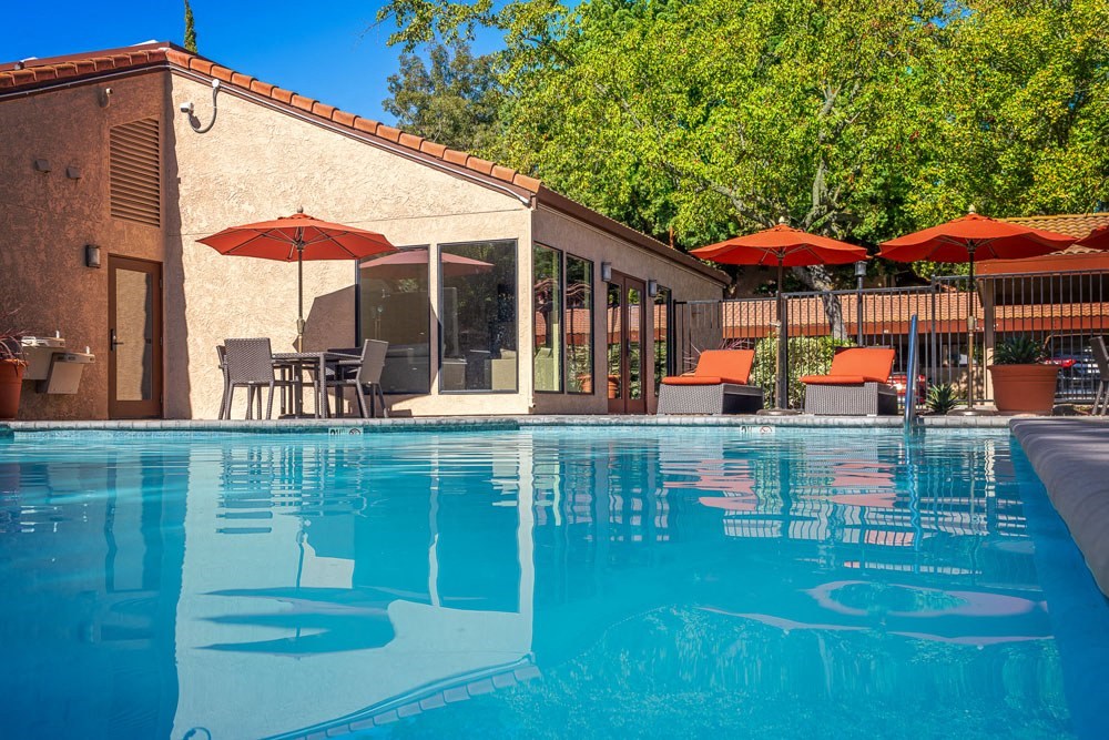 a swimming pool in front of a house with umbrellas