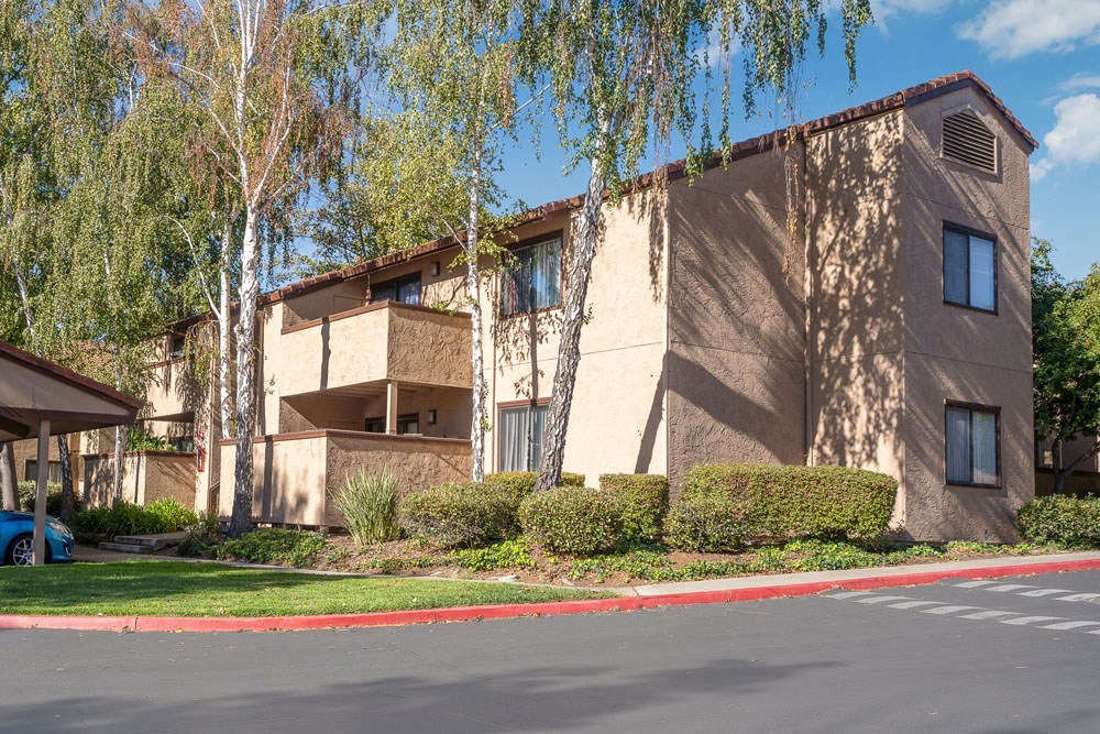 a beige apartment building with balconies and trees