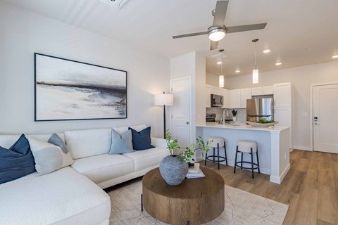 A living room with a white couch and a painting on the wall.