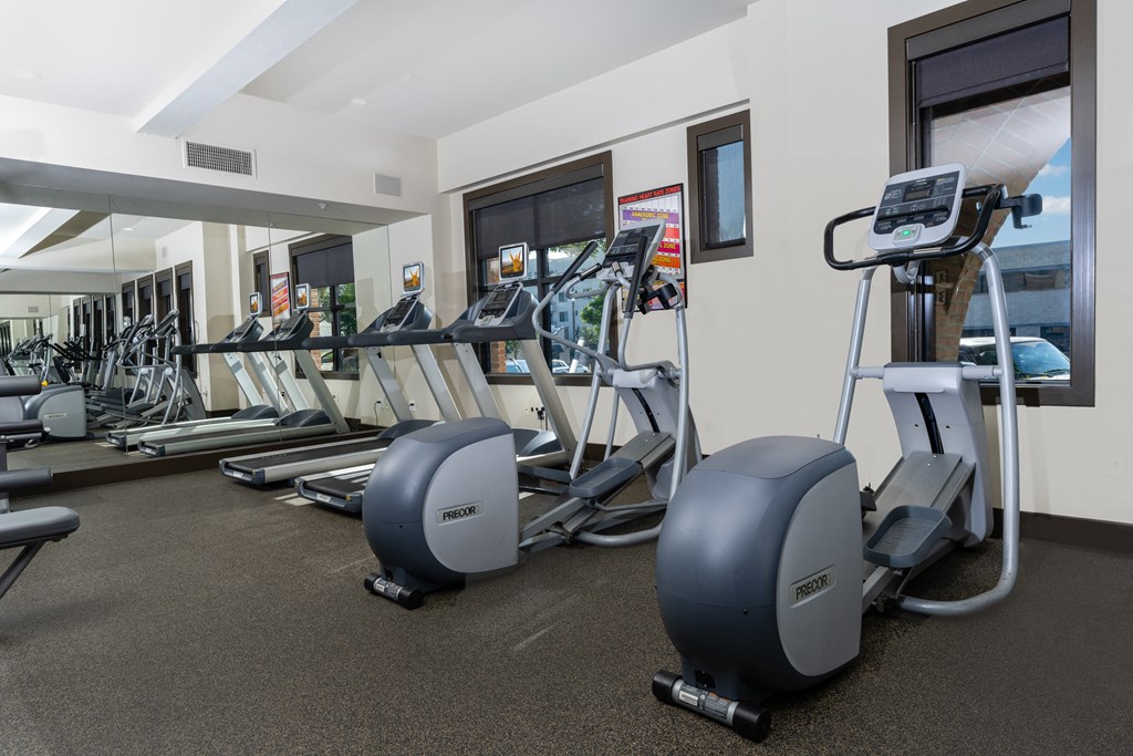 a gym with cardio equipment and weights on the floor