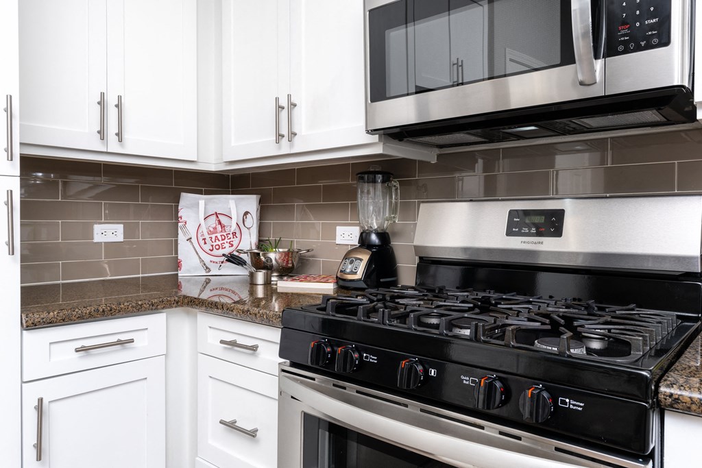 a kitchen with white cabinets and a stove and a microwave