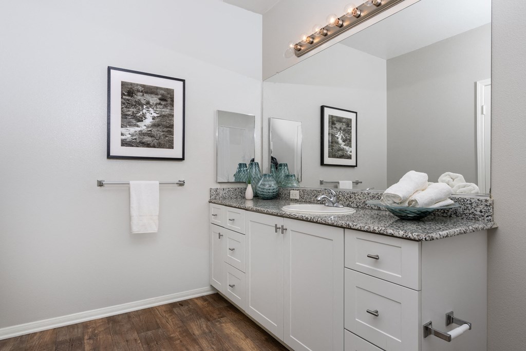 a bathroom with white cabinets and a mirror and a sink
