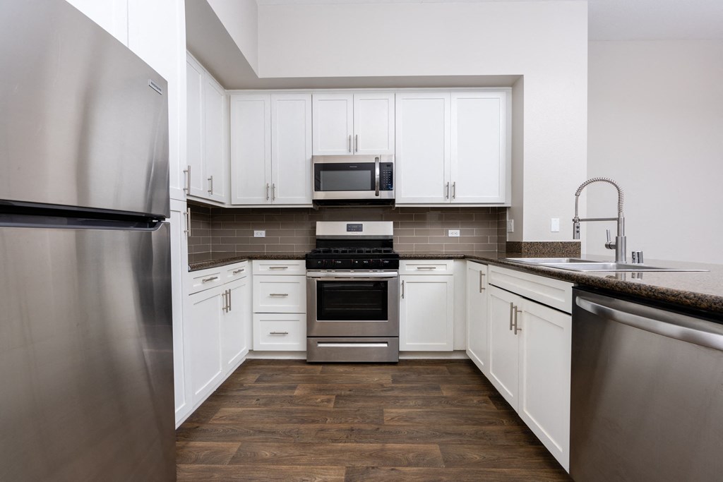 a kitchen with white cabinets and stainless steel appliances