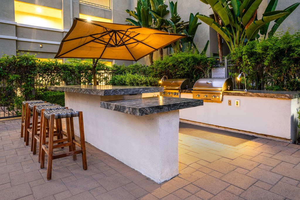 the outdoor bar area of a hotel with bar stools and an umbrella