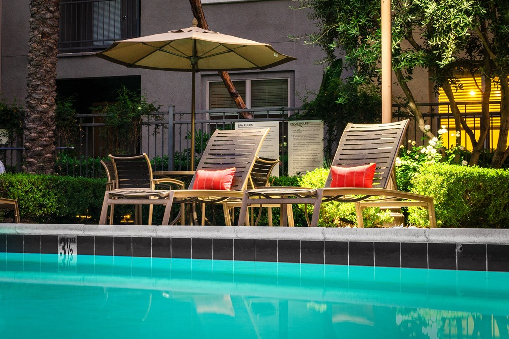 a pool with chairs and umbrellas next to a swimming pool
