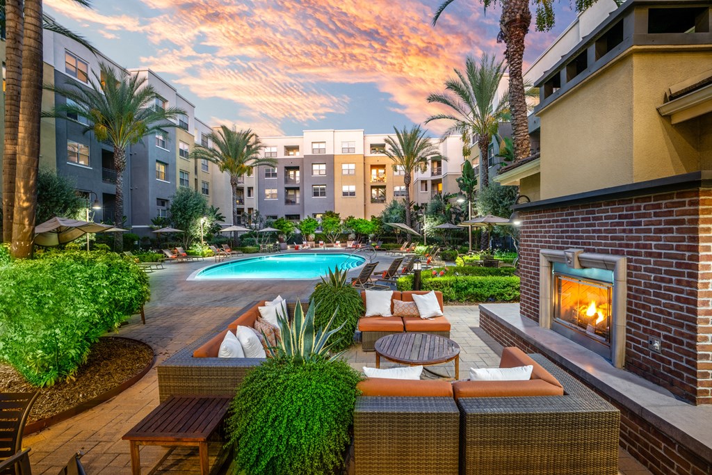 a patio with a fireplace and a pool in front of an apartment building