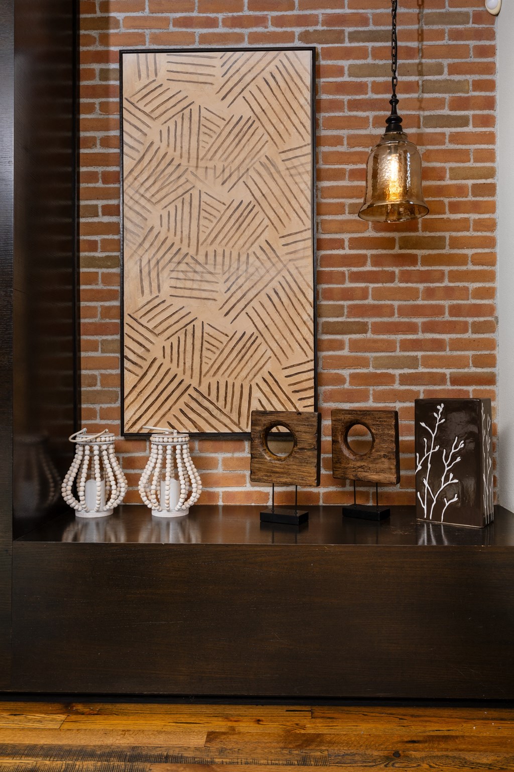 a living room with a table and a painting on a brick wall