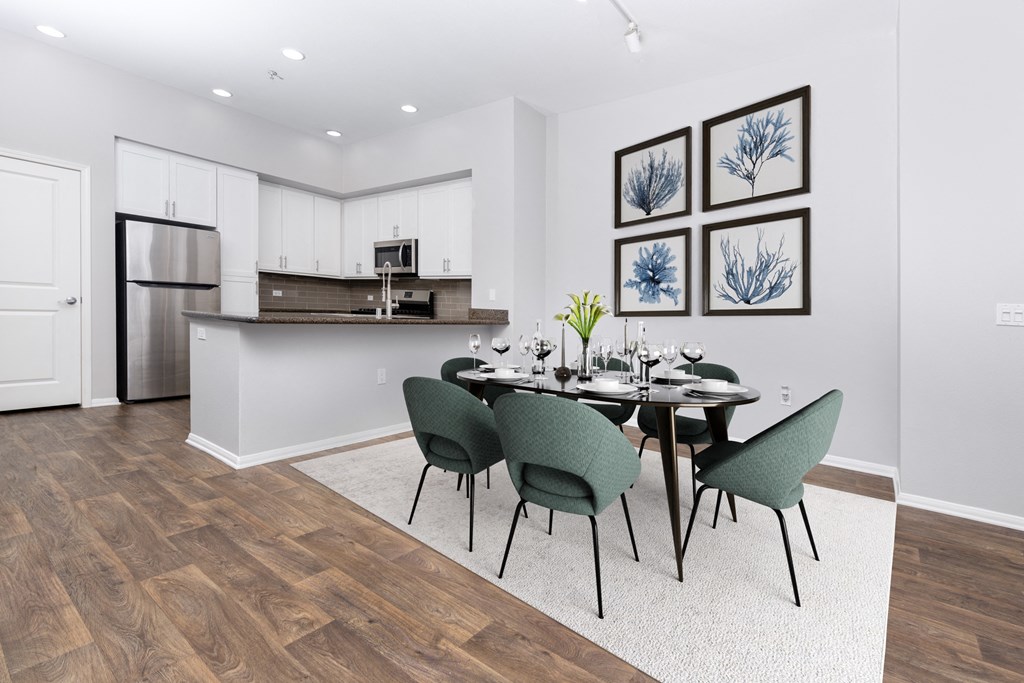 a dining area with a table and chairs and a kitchen with a refrigerator