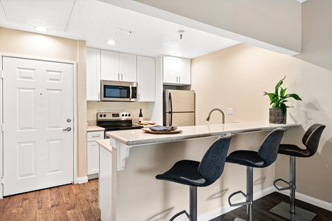 A kitchen with a white counter and black barstools.