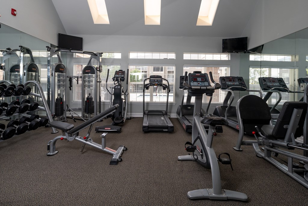 A gym with a variety of equipment including treadmills, weights, and exercise machines.
