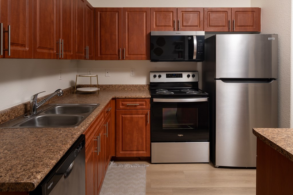 A kitchen with brown cabinets and a stainless steel refrigerator.