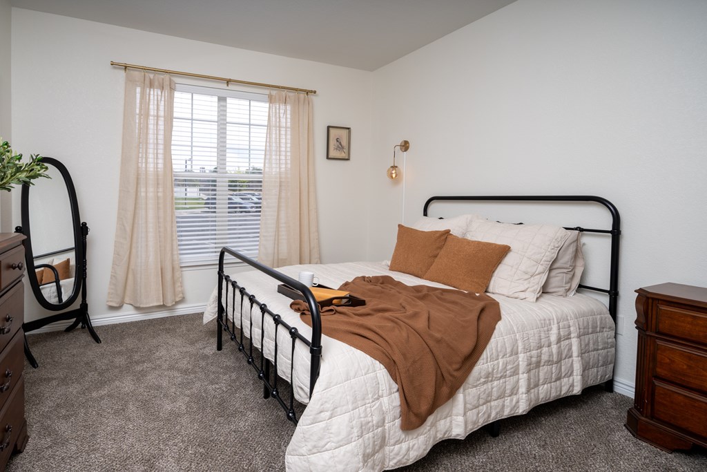 A bedroom with a bed, nightstand, and window.