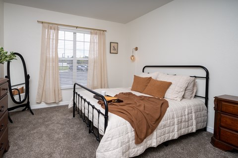 A bedroom with a bed, nightstand, and window.