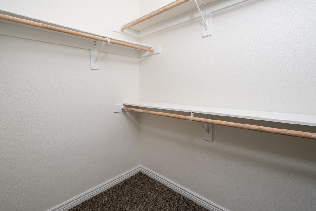 A corner of a room with a carpeted floor and two shelves.
