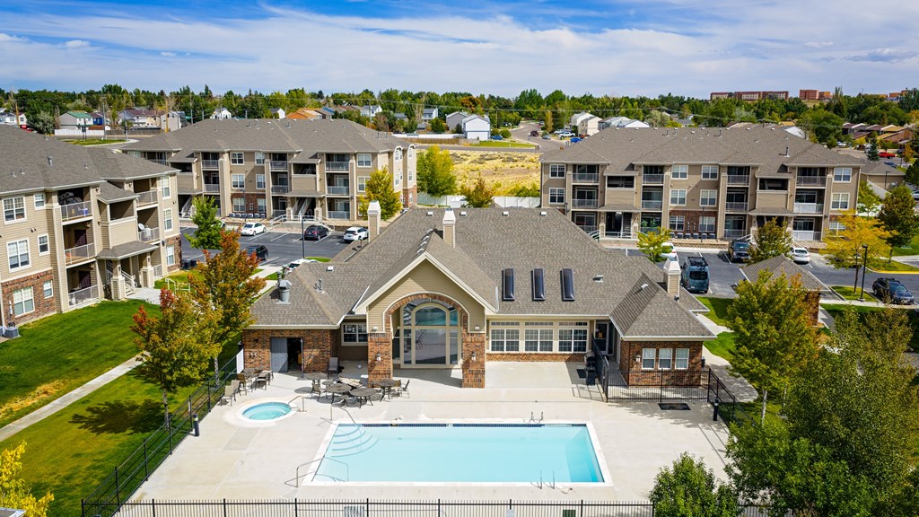 A large house with a pool in front of apartment buildings.