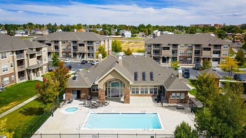 A large house with a pool in front of apartment buildings.
