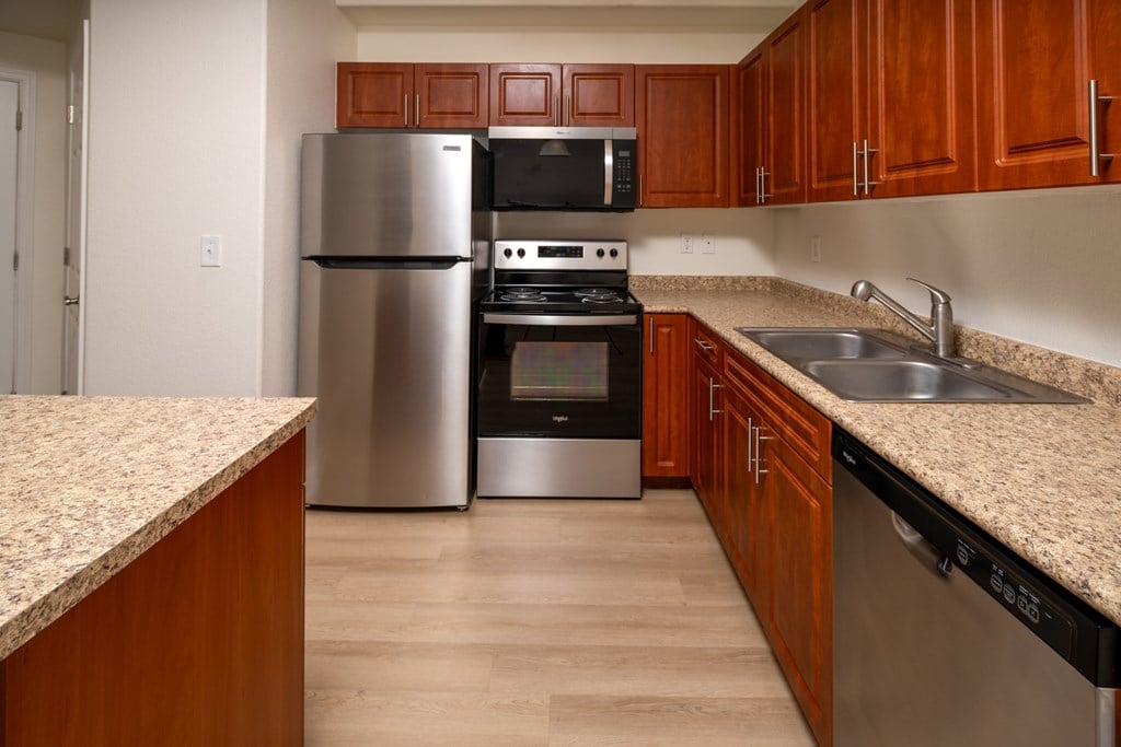 A kitchen with wooden cabinets and a granite counter.