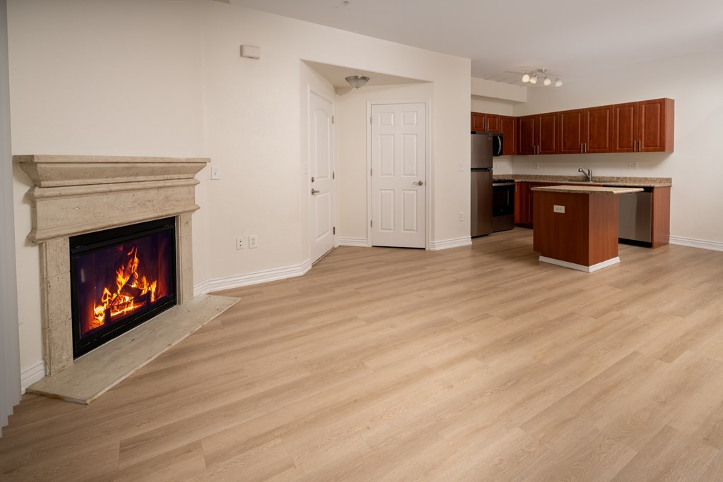 A living room with a fireplace and a kitchen area in the background.