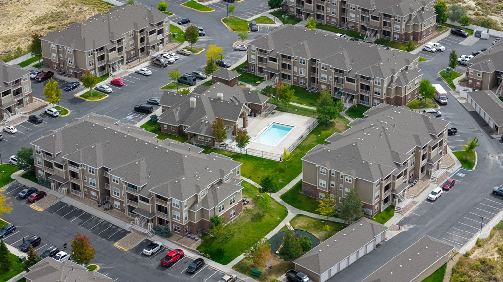 An aerial view of apartment buildings with cars parked in the driveways.