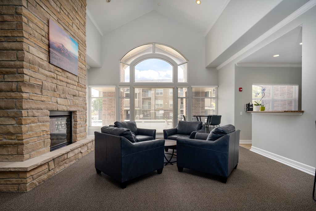 A living room with a stone fireplace and two black sofas.