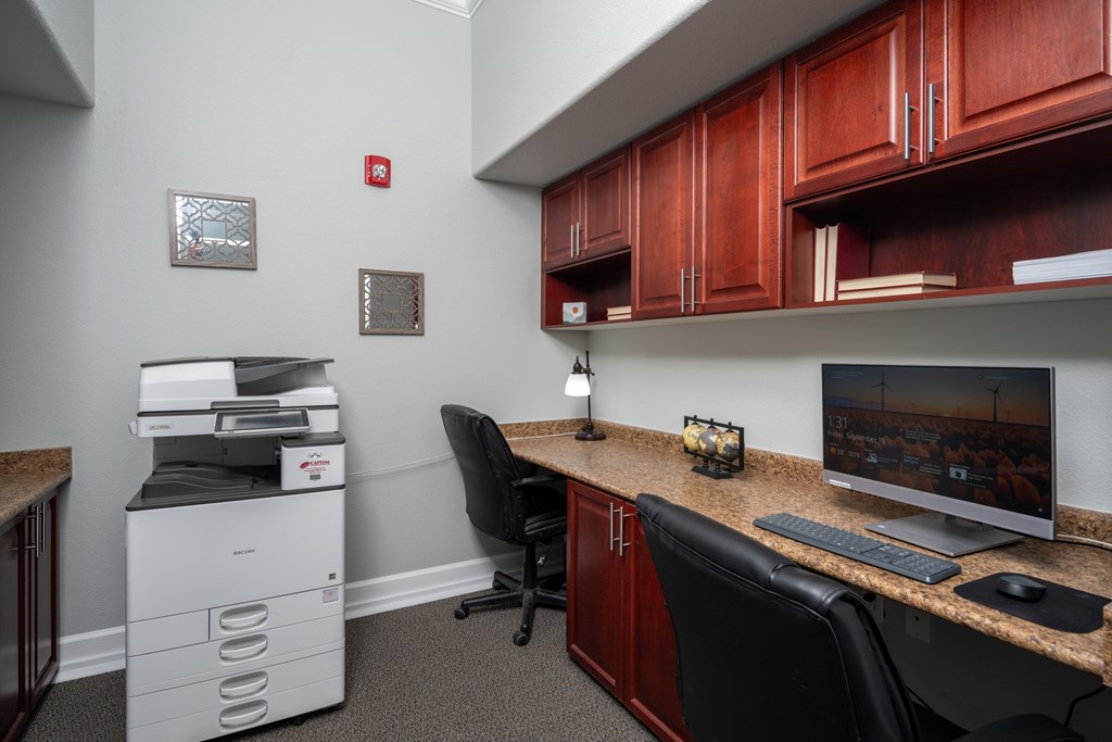 A white printer sits on a desk next to a black chair.