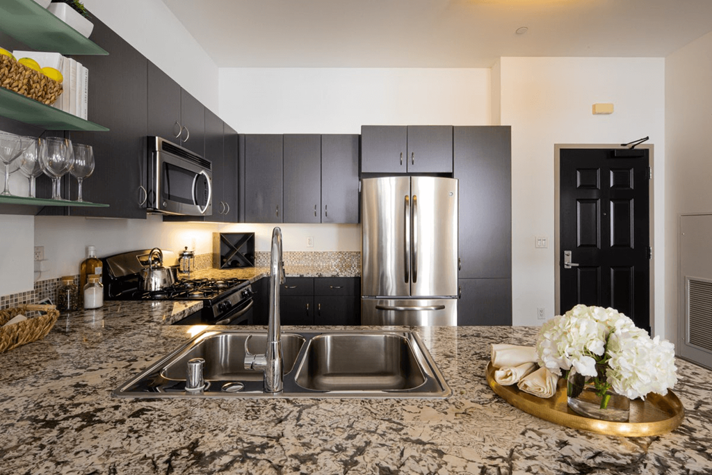 a kitchen with granite counter tops and a stainless steel refrigerator