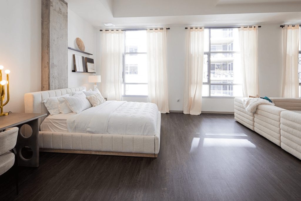 a bedroom with a bed and a couch and windows