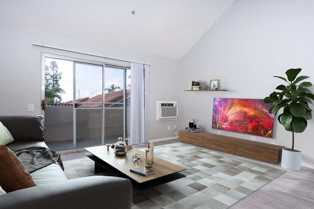 A living room with a grey couch, a coffee table, a plant, and a painting on the wall.