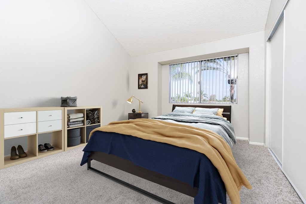A bedroom with a bed, nightstand, and a window with a view of a tree.