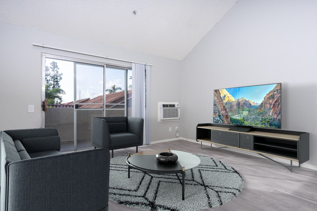 A modern living room with a large flat screen TV and a comfortable seating area.