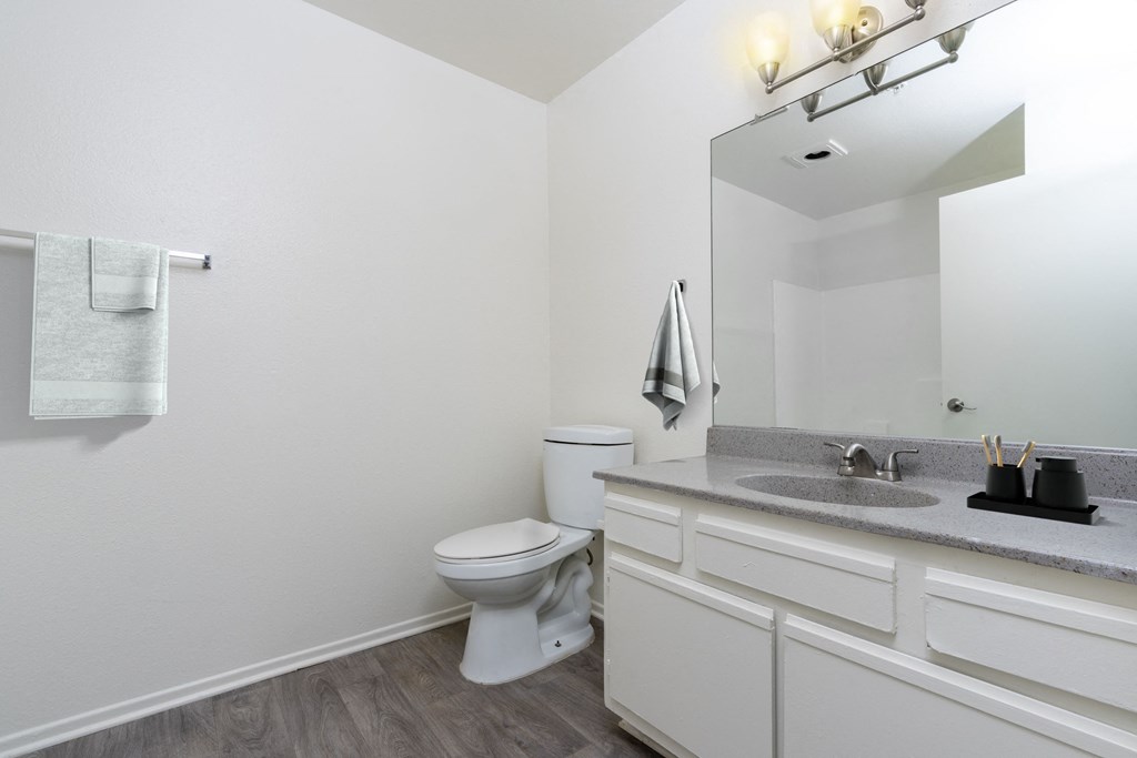 A white toilet sits in a bathroom with a white sink and a mirror.