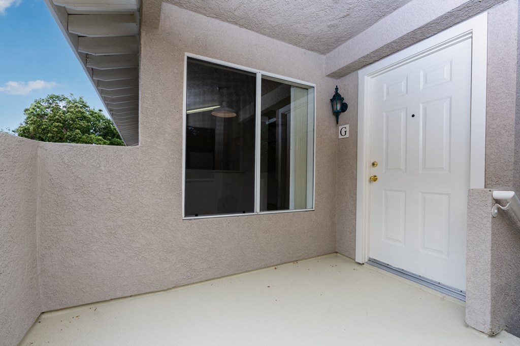 the front porch of a house with a white door and a window