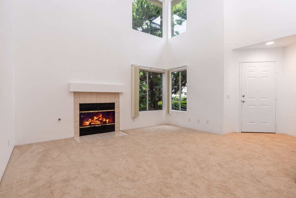 an empty living room with a fireplace and windows